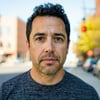 a 30 year old hispanic man head shot maybe out on a sidewalk casual but not too casual